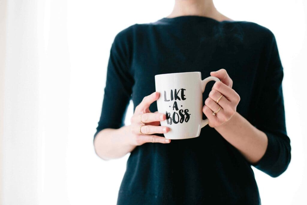 A confident businesswoman holding a mug emblazoned with 'like a boss,' symbolizing strong modern HR management in small business environments. This image represents the empowerment and leadership essential for effective HR management, showcasing the proactive and strategic approach taken in modern HR practices."