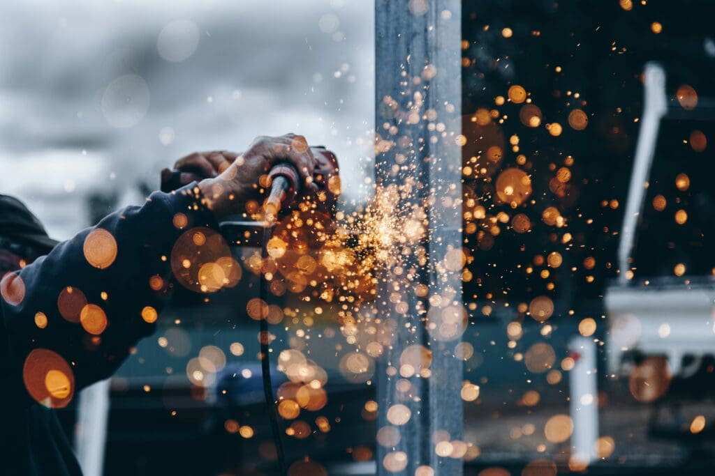 A skilled worker using a welding torch on metal components in Colorado, demonstrating adherence to safety standards and employment laws. This image represents the diligence required to maintain a Colorado compliant workplace, highlighting the importance of following regulations to ensure a safe and legal environment for employees.