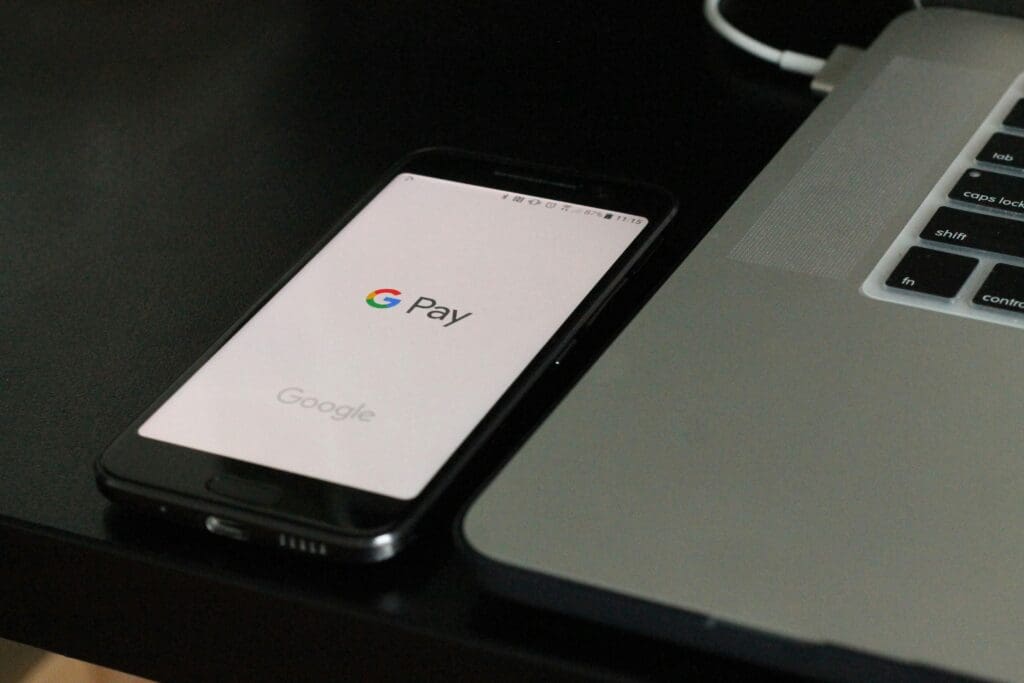 A phone and computer displaying payroll software interface alongside a digital employee handbook, illustrating the integration of technology in HR management.