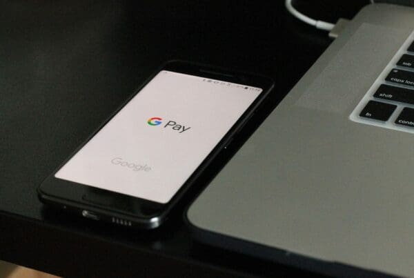 A phone and computer displaying payroll software interface alongside a digital employee handbook, illustrating the integration of technology in HR management.
